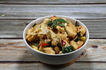 Traditional fried and stirred spicy tofu with mushroom, chilly and basil serving in the bowl. Famous spicy vegetarian menu in Asia restaurant. 