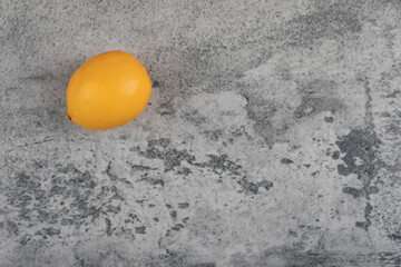 Single fresh yellow lemon placed on stone surface