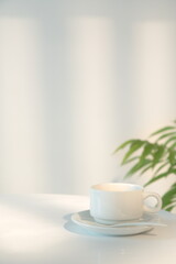 A cup of coffee on the table on beige background, morning sunlight through the window shining on the wall, copy space