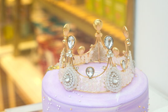 Closeup Of A Crown With Diamond On Purple Birthday Cake, Blur Background