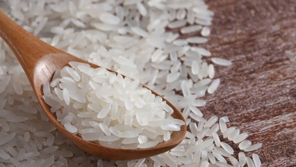 Closeup of plump rice in wooden spoon, Asian staple food, selective focus