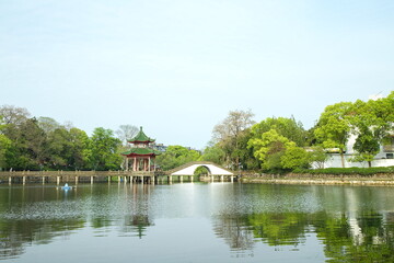 Fototapeta na wymiar Retro pavilion and stone arch bridge on the lake in the park, traditional Chinese garden landscape