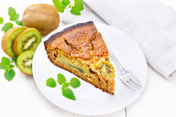 Pie with kiwi in plate on wooden board