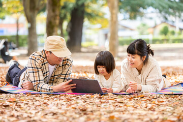 秋の公園でタブレットPCで遊ぶ家族・ファミリー
