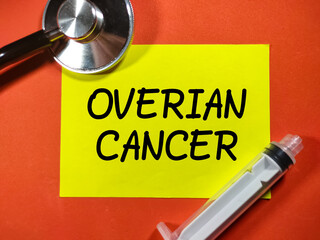 Selective focus.Word OVERIAN CANCER on color paper with stethocope and sryinge on red background.Medical concept.