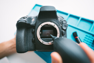 Close up of man hands cleaning a camera matrix with dust cleaner, air blower or vacuum pump. Photography equipment care