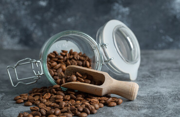 Glass jar of aromatic coffee beans on marble background