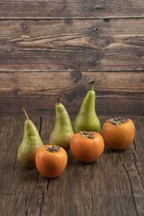 Delicious fuyu persimmons and ripe pears on wooden surface