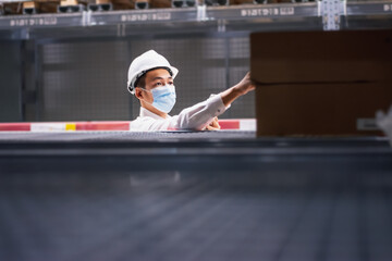 Asian handsome engineer or technician wearing mask,and safety hard hat,uses digital tablet check merchandise stock,security cargo management,in warehouse,industry business  logistic and export concept