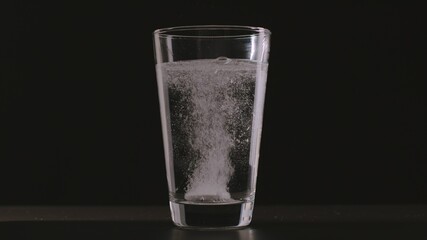 White instant pill into glass of water and dissolves
