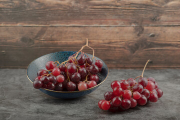 Deep plate of red ripe grapes on marble table