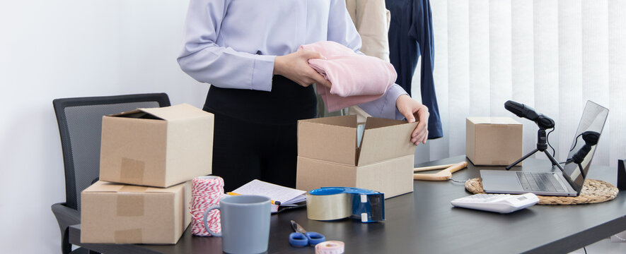 Young Asian women pack their clothes into boxes and prepare them to be delivered by post, Online clothing sales business, Business of selling clothes on social media or selling online.