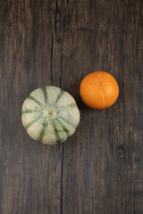 Whole healthy orange fruit with gray pumpkin on wooden table