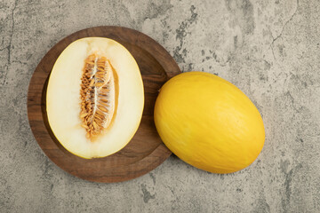 Halved and whole delicious yellow melon on wooden plate