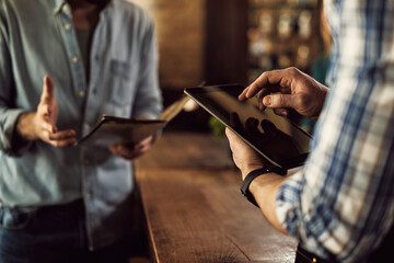 Close-up of waiter taking order on digital tablet in a cafe.