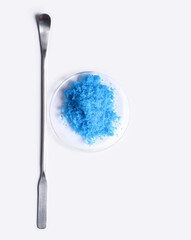 Copper(II) sulfate in Chemical Watch Glass placed next to the stirring rod on laboratory table.