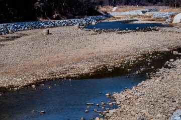 Very shallow river with rocky bed in wilderness park.
