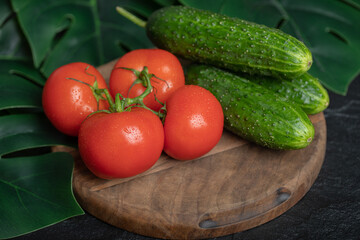 Pile of fresh organic vegetables. Cucumbers and tomatoes on wooden board