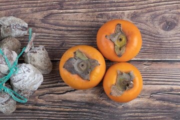 Fototapeta na wymiar Tasty fuyu persimmons and dried persimmons on wooden surface