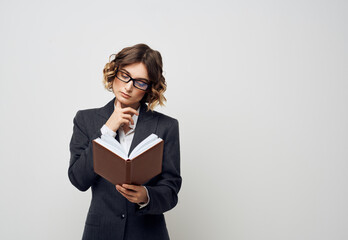 Fototapeta premium Business woman with a book in her hands on a light background Puzzled look Copy Space