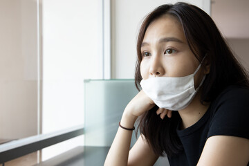 young Asian woman improperly wearing face mask, concept of wearing face mask in wrong way, ignoring...