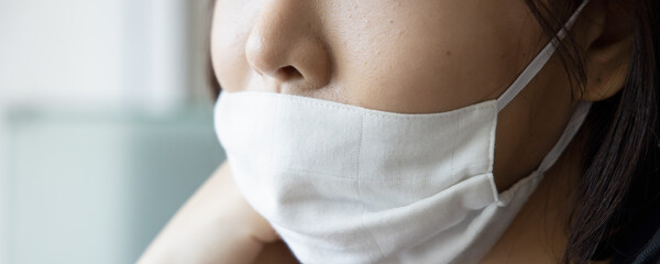 young Asian woman improperly wearing face mask, concept of wearing face mask in wrong way, ignoring...