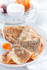 Thin openwork pancakes with apricot jam, selective focus