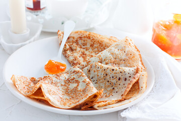 Thin openwork pancakes with apricot jam, selective focus