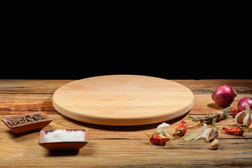 Culinary background.Wooden round cutting board, knife, spices for cooking on an old rustic table, close-up.A place for the cook.Selective Focus