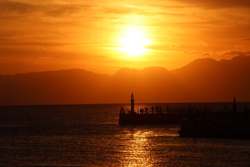 Fototapeta premium 片瀬江ノ島海岸から見る伊豆半島に沈むオレンジ色の夕日と堤防のシルエット