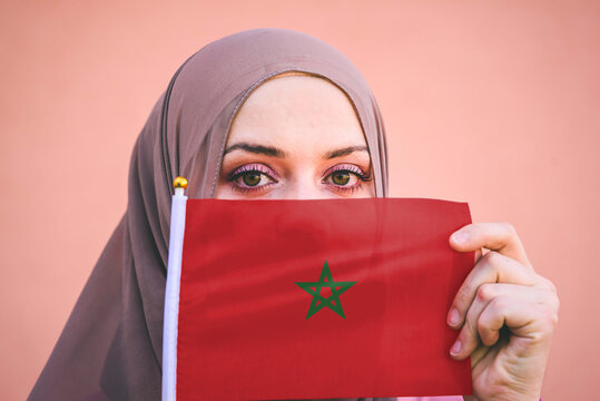 Muslim woman in hijab holds flag of Morocco
