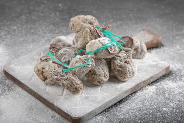 Dried persimmon fruits decorated with flour on black surface