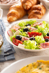 Healthy salad in a bowl with olives, raddishes, tomato, cheese and lean ham served for breakfast
