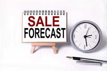 Sale Forecast. text on white notepad paper on white background. near the table clock