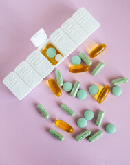 Different pharmaceutical medicine pills, tablets and white pill case on pink background. Health care. Top view. Pharmaceutical picture. 