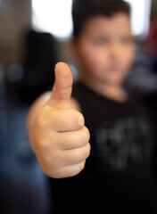 The boy shows a thumb up on his hand.