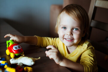 Little cute boy playing with cars on a table.