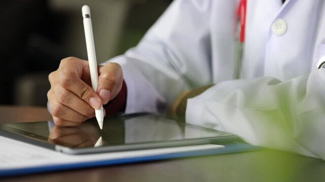Image hand Close-up of an Asian doctor in uniform and stethoscope reading patient report on a digital tablet by concept online medical