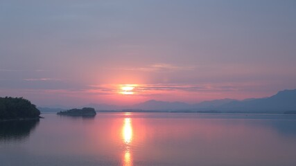 Fototapeta na wymiar Orange sunset reflecting on the water; beautiful lake scenery in the evening