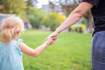 Fototapeta premium Mother and daughter holding hands. Family love and care concept.