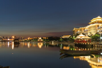 Fototapeta premium Bright city buildings at night. Dragon boat parked on water