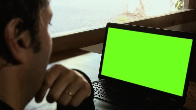 Man using Laptop Computer Green Screen on Cafe Table. Zoom In. You can replace green screen with the footage or picture you want. You can do it with “Keying” effect in After Effects. 4K.