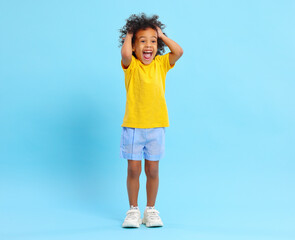 Cheerful black kid touching hair and screaming happily in blue studio