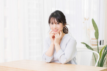 部屋で肘をついて座っている若い女性