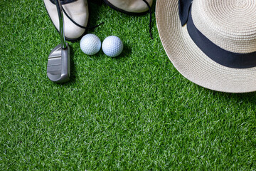 Golf ball with putter shoe hat are on green grass