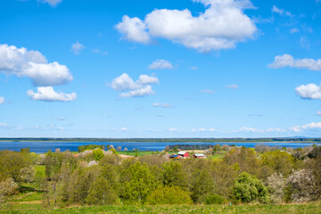 View at a lake in a rural landscape with budding trees and a farm