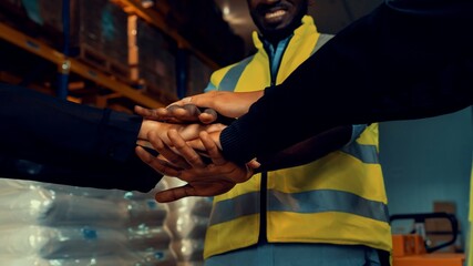 Factory workers stacking hands together in warehouse or storehouse . Logistics , supply chain and...