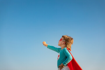 Superhero child against blue summer sky background