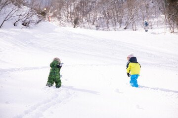 男の子と女の子がスキーウェアーを着てスキー場を登っている　winter