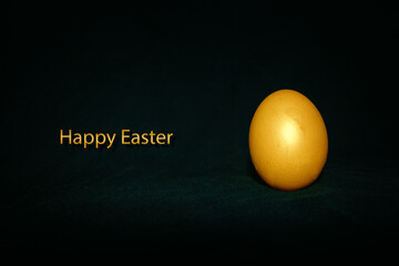 A golden colored egg on a dark green background. Caption: "Happy Easter."